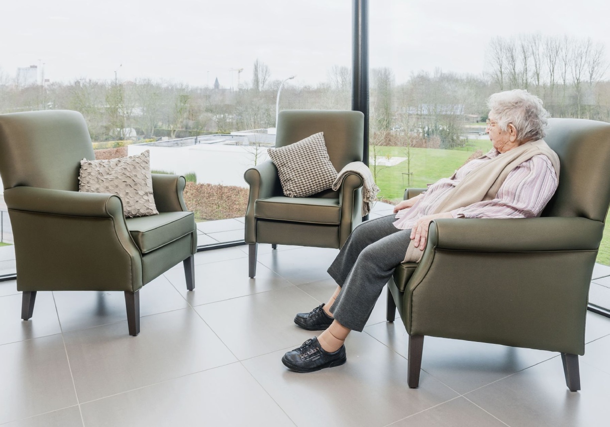 mujer mayor sentada en un sillon verde